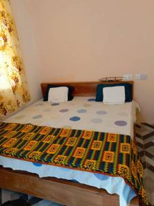 BusuaPalm Grove lodge的一间卧室配有一张带五颜六色棉被的床