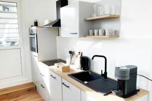 门兴格拉德巴赫Großzügiges City-Apartment in Mönchengladbach的厨房配有白色橱柜和黑色水槽