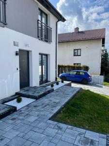 兰卡特Apartament Skłodowskiej的停在白色房子前面的蓝色汽车