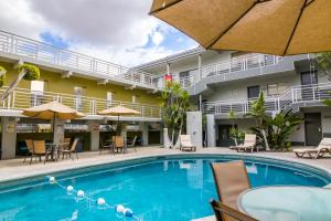 提华纳Baja Inn Hoteles La Mesa的酒店前的游泳池配有椅子和遮阳伞