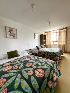 伊察El Huerto Hostel的酒店客房 - 带2张床和花卉床罩
