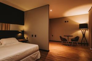 卡夸尔Catuai Hotel的卧室配有一张床和一张桌子及椅子