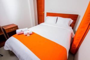 阿亚库乔La Villa de Roel的橙色和白色的床,带两条毛巾