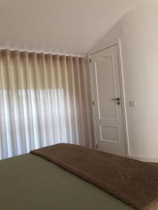 维埃拉·多米尼奥Sobreiro Valley - Casa Isabel的一间卧室设有门,窗户设有窗帘