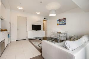 奥克兰Bright & modern Auckland CBD apartment的白色的客厅配有白色的沙发和桌子