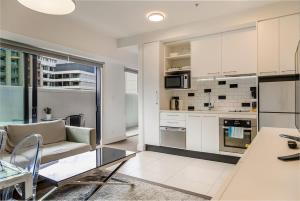 奥克兰Bright & modern Auckland CBD apartment的厨房以及带沙发和桌子的客厅。