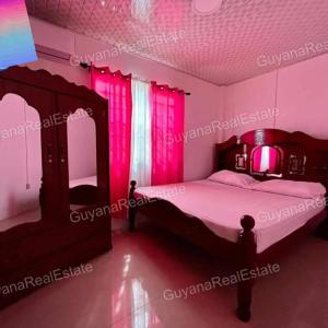 乔治敦S&S Guyana Real Estate Apartment的一间卧室配有粉红色照明床