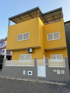 普拉亚BemVinda Sweet Home - Cama Mesa e Fogão的黄色的建筑,旁边设有阳台
