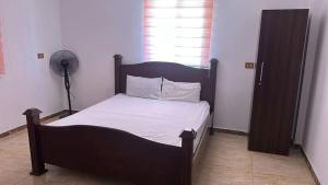 阿杰隆Green forest farm的一间卧室配有一张带白色床单的木床和风扇。