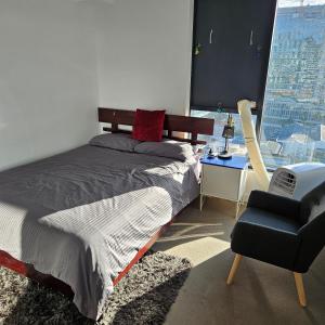 布里斯班Bedroom & Private Bathroom in Modern Inner Brisbane Apartment的卧室配有床、椅子和窗户。