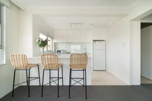 悉尼Harbourside #49的厨房配有3个吧台凳和1个带冰箱的台面