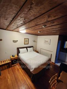 坎贝尔河Campbell River Lodge的一间卧室设有一张床和木制天花板