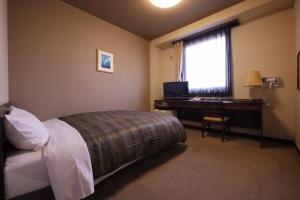 长野筱之井如特酒店的一间卧室配有一张床、一张书桌和一个窗户。