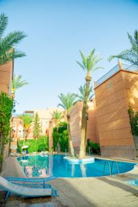马拉喀什Riad The Moroccans Pool And Terrace的一座棕榈树游泳池,位于酒店大楼旁
