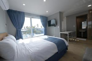 西归浦市Sweet Stay Pension的一间卧室设有一张大床和一个窗户。