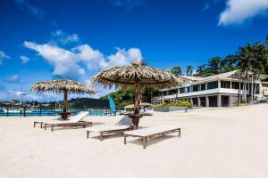维拉港伊利利奇岛Spa度假酒店的海滩上的两把椅子和两把遮阳伞