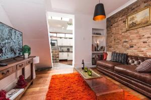悉尼Modern Sydney Surry Hills Century Cottage的客厅设有棕色的沙发和砖墙
