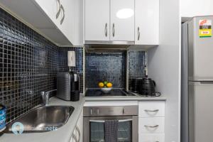 悉尼Studio Gem With Rooftop Space Prime Location的小厨房配有白色橱柜和水槽