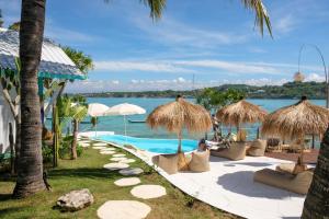 蓝梦岛Le Pirate Beach Club Nusa Ceningan - Adults Only的一个带游泳池和稻草遮阳伞的度假村