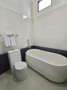 坤甸哈默尼酒店和卡拉OK的白色的浴室设有浴缸和卫生间。