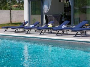 罗波里卡Ferienhaus mit Privatpool für 10 Personen ca 300 qm in Loborika, Istrien Südküste von Istrien的游泳池旁的一排蓝色躺椅