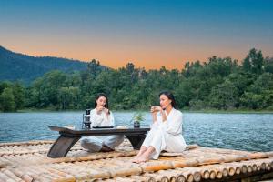 邦美蜀The Coffee City - Healing & Retreats的两个坐在湖上野餐桌上的女人