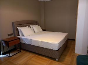 基加利ACACUS LUXURY的一张带白色床单和枕头的床
