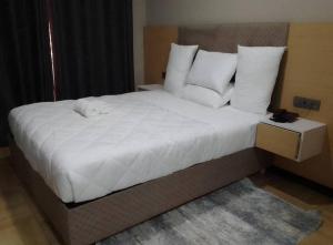 基加利ACACUS LUXURY的卧室配有一张带白色床单和枕头的大床。
