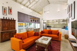 斯里贾亚瓦德纳普拉科特Angam Suites Colombo的客厅配有2张橙色沙发和1张桌子