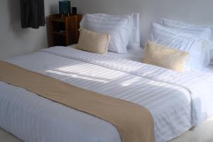 外南梦LAYANA FARMSTAY的一张白色大床,配有白色床单和枕头