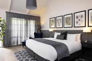 赫本温泉Mineral Springs Hotel Hepburn的卧室配有一张白色大床和一把椅子