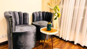 伊斯兰堡Executive One Bedroom Apartment Opposite Centaurus Mall Islamabad的一间设有两把椅子和一张带花瓶的桌子的房间