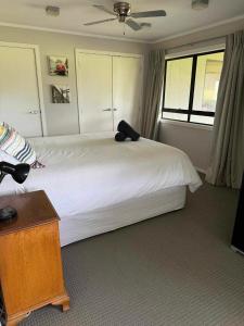 芒格努伊山Coastal Golf & Spa Guesthouse的卧室配有一张白色的床和黑色枕头