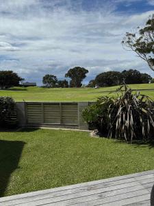 芒格努伊山Coastal Golf & Spa Guesthouse的一个带栅栏的花园和一个种有树木的田野
