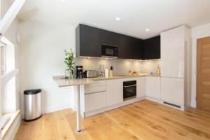 伦敦Central Fitzrovia - 1BR - CityApartmentStay的厨房铺有木地板,配有白色橱柜。