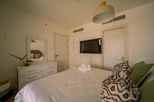 阿布扎比Raha Lofts Hosted By Voyage的一间卧室配有一张带梳妆台和电视的床。