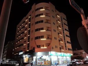 阿吉曼AL MARJAN FURNISHED APARTMENTS的前面有一间商店的高楼