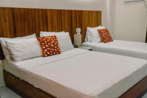 宿务蔡酒店及公寓的配有2张床铺的酒店客房,提供白色和橙色枕头