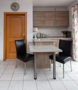 博尔库姆Ferienhaus Inselkate的厨房配有桌子和2把黑色椅子