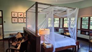大叻Ana Mandara Villas Dalat Resort & Spa的一间卧室配有一张带灯和椅子的天蓬床