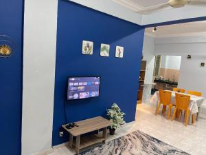艾尔克如Serene Bukit Beruang Cottage 4 ROOMS FULL AIRCOND & NETFLIX by EZYROOM MELAKA的客厅的蓝色墙壁,配有桌子