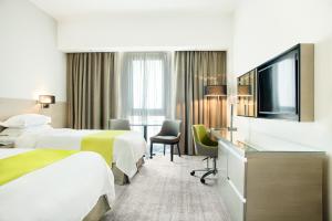 马斯喀特Novotel Muscat Airport的酒店客房设有两张床和一台平面电视。