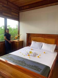 森莫诺隆Samnang Leap guesthouse的站在床边的女人,床上花