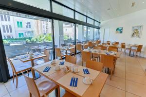 洛迦诺哈尼穆拉尔托酒店的餐厅设有木桌、椅子和窗户。