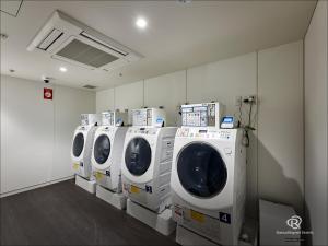 埼玉市Daiwa Roynet Hotel Omiya-nishiguchi的洗衣房里的一排洗衣机和烘干机