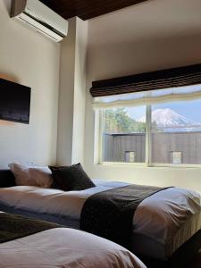 富士吉田市SWEET VILLA TAKASAMA的一间带两张床的卧室和一扇享有山景的窗户