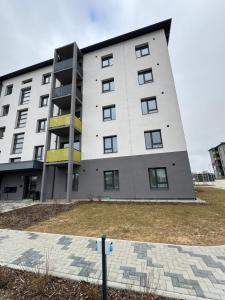 DreiliņiModern 4-Room compact flat with parking in Riga的白色的大建筑,带有黄色的点缀