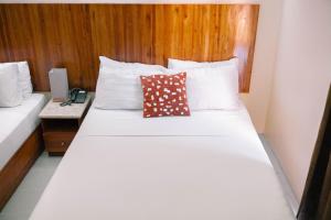 宿务蔡酒店及公寓的卧室配有白色的床和木制床头板