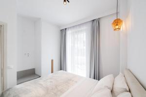 雷夫卡达镇SunilioS Apartments Lefkada的白色的卧室设有一张大床和一个窗户