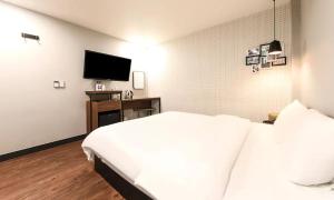 釜山No 25 Hotel Gwangan的卧室配有白色的床和平面电视。